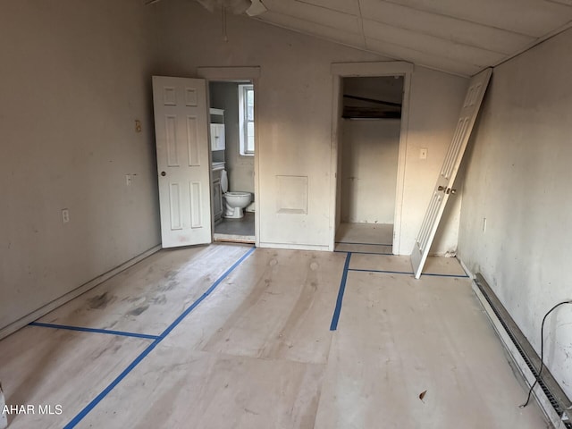 unfurnished bedroom featuring connected bathroom, vaulted ceiling, and a baseboard heating unit