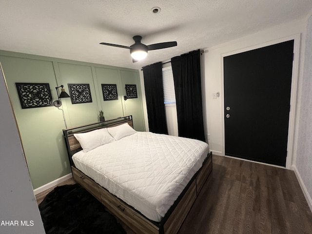 bedroom with a textured ceiling, ceiling fan, and dark wood-type flooring