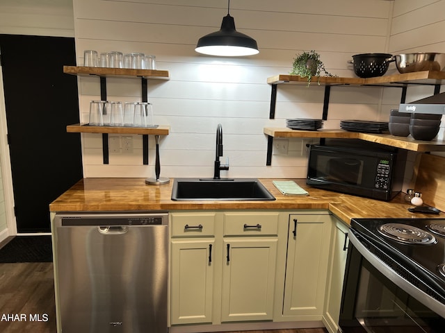 kitchen featuring dark wood-type flooring, black appliances, sink, decorative light fixtures, and butcher block counters