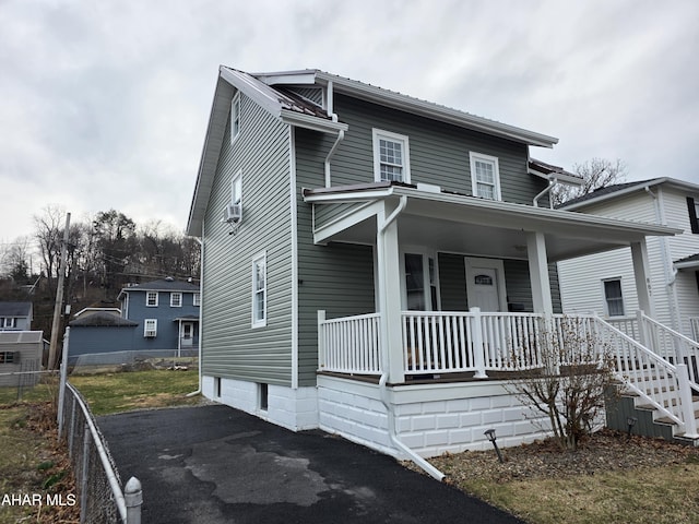 view of front of house featuring aphalt driveway, fence, and covered porch