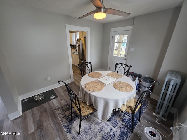 dining area featuring baseboards, radiator heating unit, a ceiling fan, and wood finished floors
