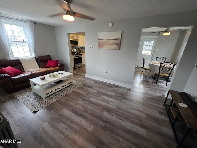 living area featuring a textured ceiling, baseboards, a ceiling fan, and wood finished floors