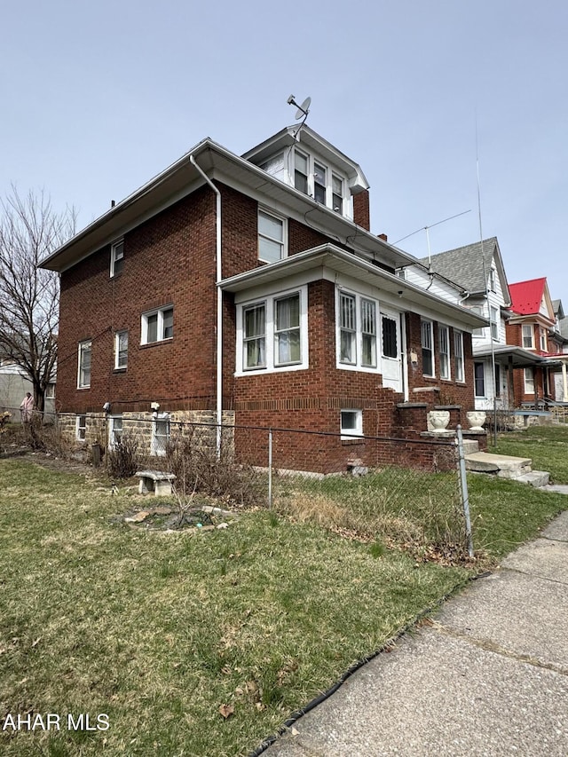 view of side of home featuring a yard, brick siding, and fence