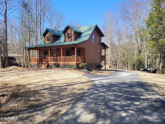 log home with a porch, log siding, and driveway