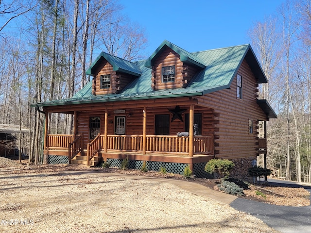 cabin with log siding, a porch, and metal roof