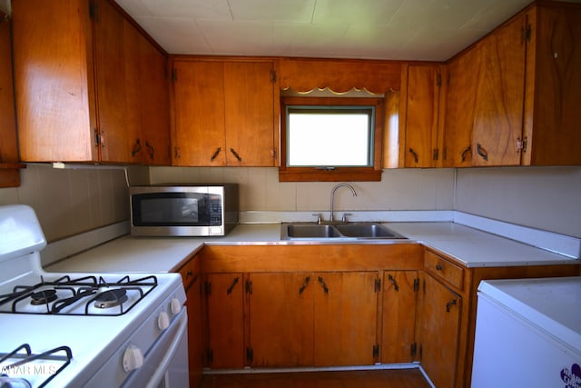 kitchen featuring a sink, stainless steel microwave, white gas range, and light countertops