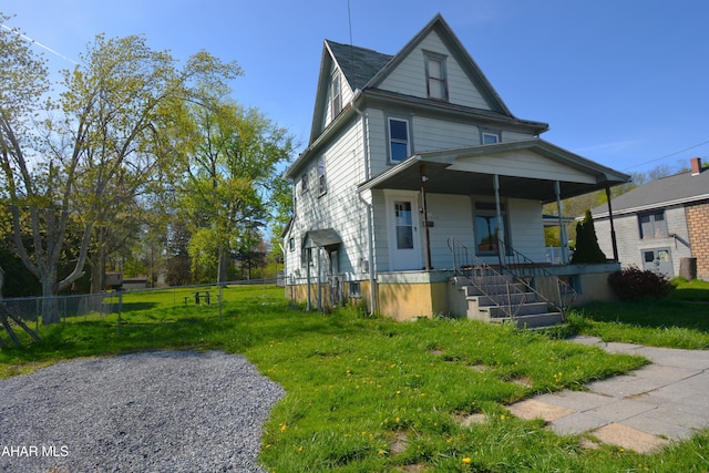 traditional style home with covered porch, fence, and a front yard