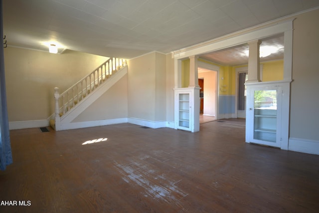 unfurnished living room with baseboards, ornamental molding, decorative columns, and wood finished floors