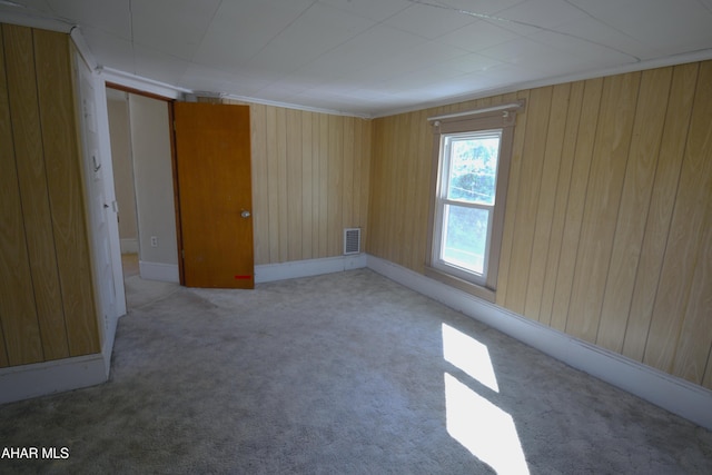 carpeted empty room with wood walls and visible vents