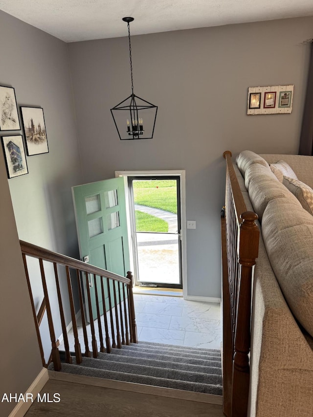 entryway featuring baseboards, a chandelier, and wood finished floors