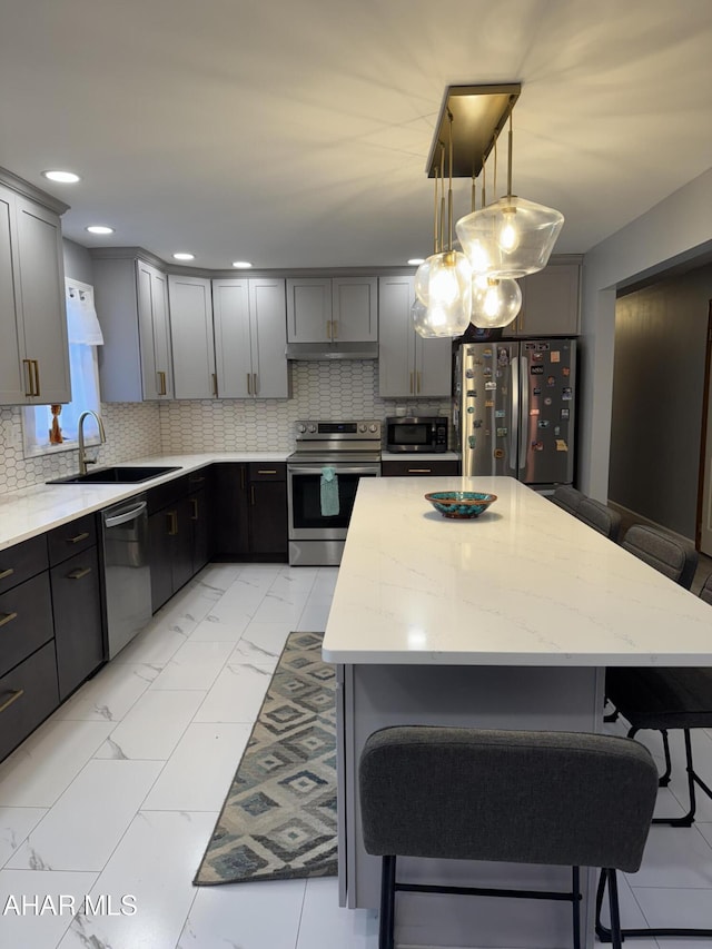 kitchen with marble finish floor, a kitchen breakfast bar, tasteful backsplash, a sink, and stainless steel appliances