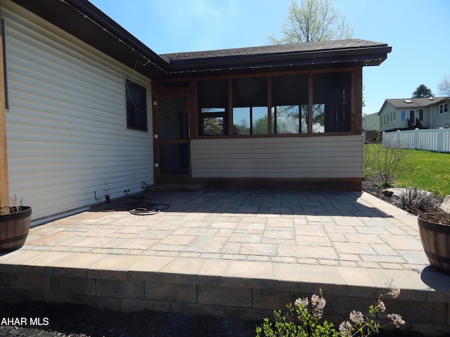 view of patio with a sunroom and fence