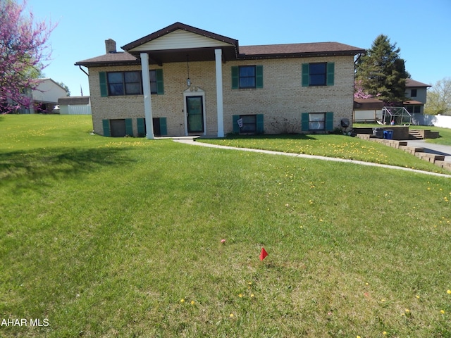 raised ranch with brick siding, a front lawn, and a chimney