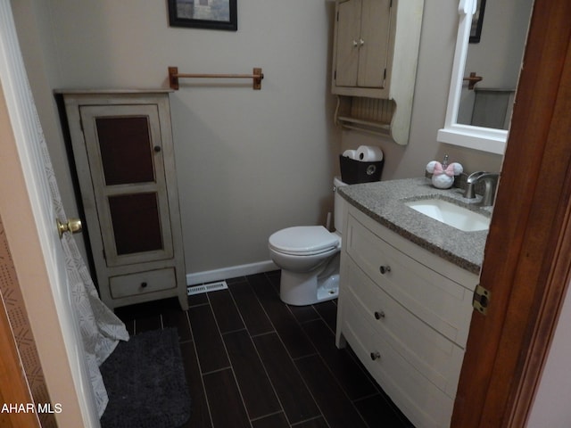 half bathroom with toilet, baseboards, visible vents, and vanity