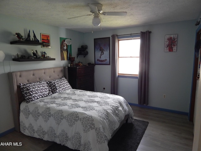 bedroom with baseboards, ceiling fan, a textured ceiling, and wood finished floors