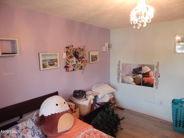 bedroom featuring a textured ceiling, visible vents, wood finished floors, and a chandelier