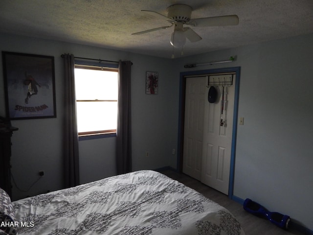 bedroom featuring wood finished floors, a textured ceiling, ceiling fan, and a closet