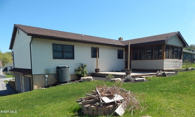 back of house featuring a sunroom, central AC unit, a lawn, and a chimney