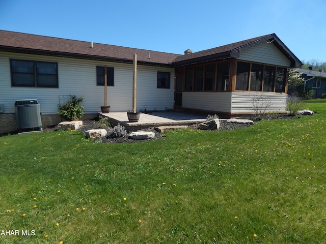 rear view of property featuring a yard, a patio, a sunroom, and central AC
