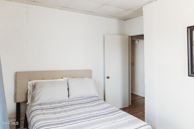 bedroom with a drop ceiling and wood-type flooring