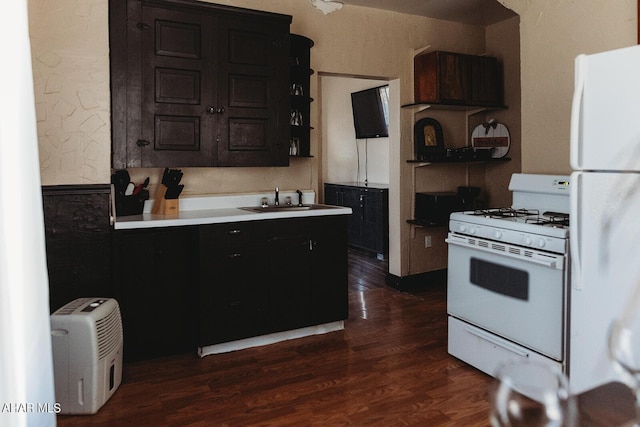 kitchen with dark hardwood / wood-style floors, dark brown cabinetry, white appliances, and sink