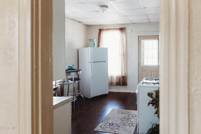 kitchen featuring a paneled ceiling, dark hardwood / wood-style floors, white refrigerator, and range