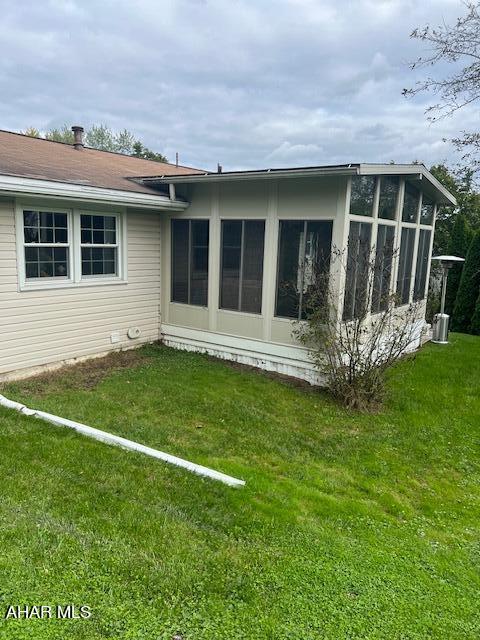 back of house with a sunroom and a lawn