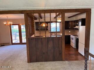 1012 Gray Ln, Duncansville, PA 16635 - kitchen featuring dark brown cabinetry, freestanding refrigerator, a chandelier, dark carpet, and range hood