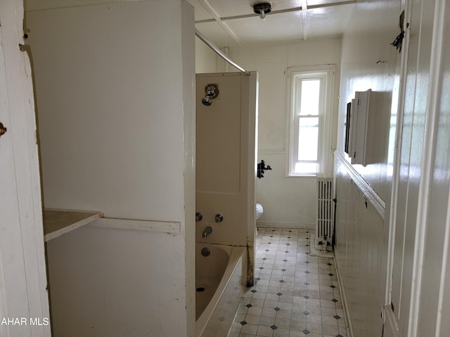 bathroom with radiator heating unit, washtub / shower combination, and toilet