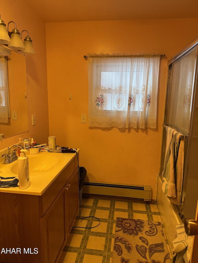 bathroom featuring tile patterned flooring, vanity, a baseboard heating unit, and a shower with shower door