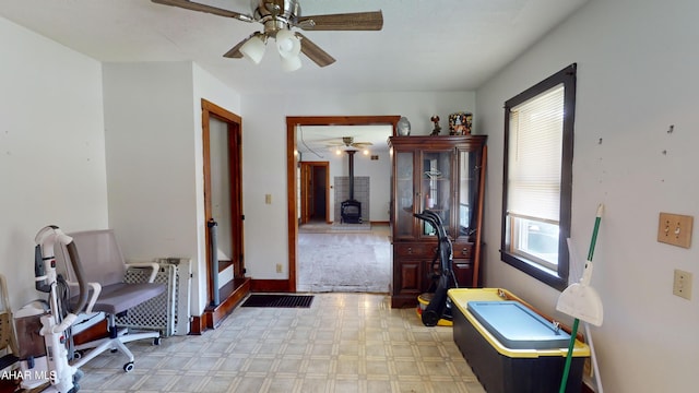 interior space with a wood stove and ceiling fan