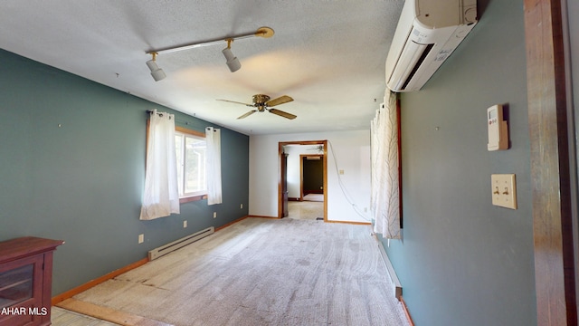 spare room with ceiling fan, a baseboard radiator, a wall mounted air conditioner, a textured ceiling, and track lighting