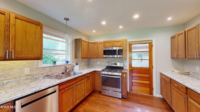 kitchen featuring sink, light hardwood / wood-style floors, decorative light fixtures, and appliances with stainless steel finishes