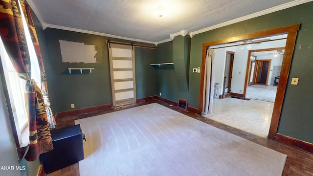 unfurnished room with a textured ceiling, a barn door, and crown molding