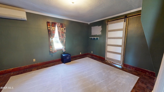 spare room with a textured ceiling, a barn door, a wall unit AC, and crown molding