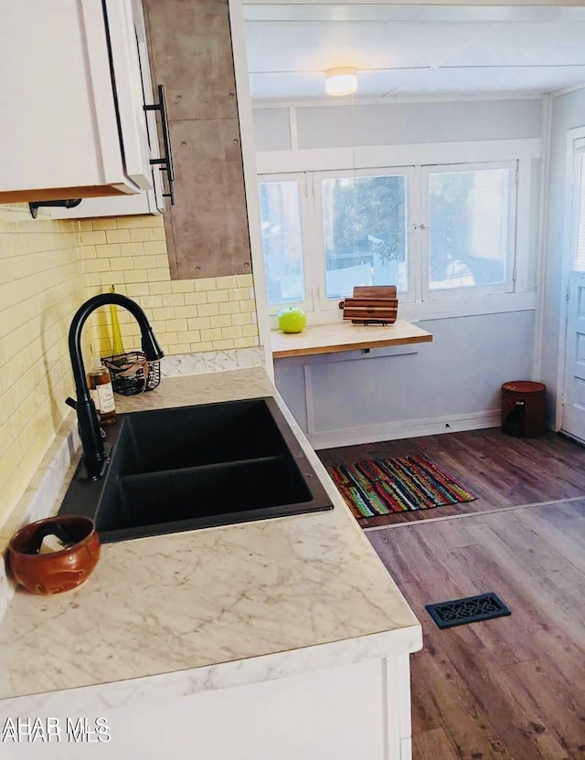 kitchen featuring white cabinets, backsplash, hardwood / wood-style flooring, and sink