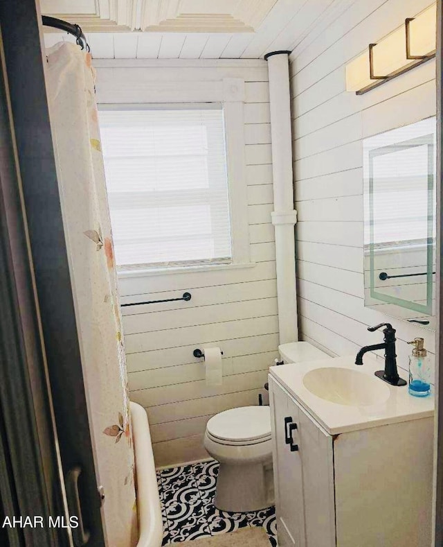 bathroom with wooden walls, plenty of natural light, wooden ceiling, and toilet