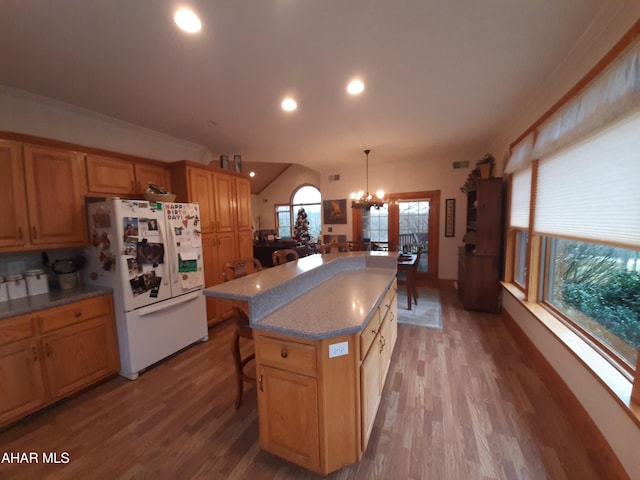 kitchen with a breakfast bar, white refrigerator, decorative light fixtures, a center island, and light hardwood / wood-style floors