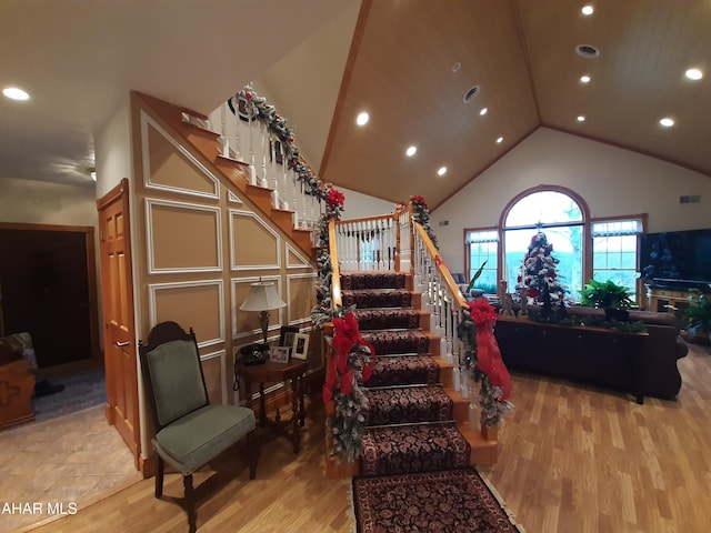 stairway with hardwood / wood-style floors and high vaulted ceiling