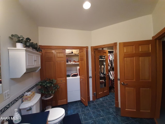 bathroom featuring toilet and washer / clothes dryer