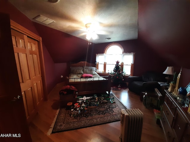 bedroom featuring a textured ceiling, hardwood / wood-style flooring, ceiling fan, and lofted ceiling