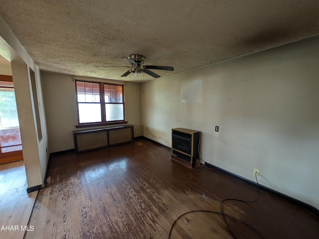 unfurnished room with dark hardwood / wood-style floors, radiator, a wood stove, and a wealth of natural light