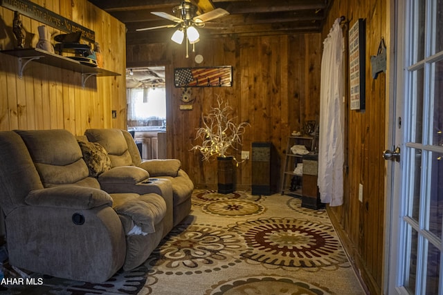 interior space featuring ceiling fan, beamed ceiling, and wood walls