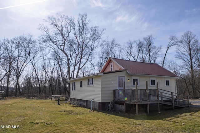 exterior space with a yard, metal roof, a wooden deck, and stairs