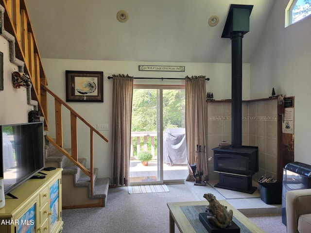 living room featuring a wood stove, carpet, stairway, and lofted ceiling