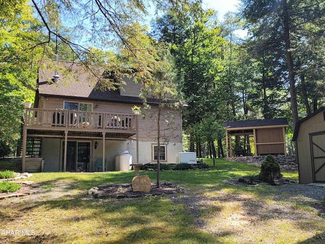 rear view of property with a lawn, a deck, an outdoor structure, a shed, and stucco siding