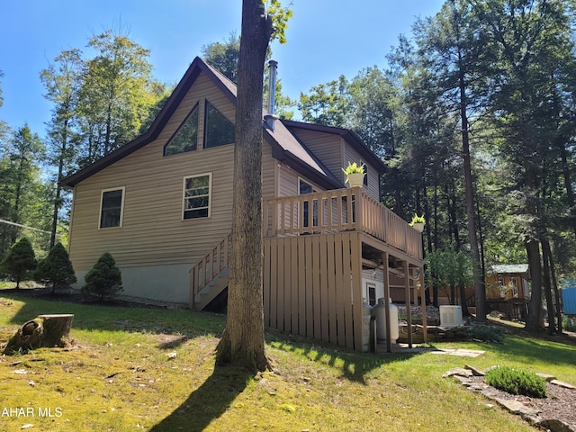 view of side of property featuring a lawn, a deck, and stairs