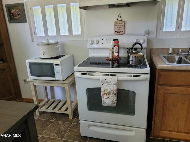 kitchen featuring brown cabinets, white appliances, a sink, and a healthy amount of sunlight