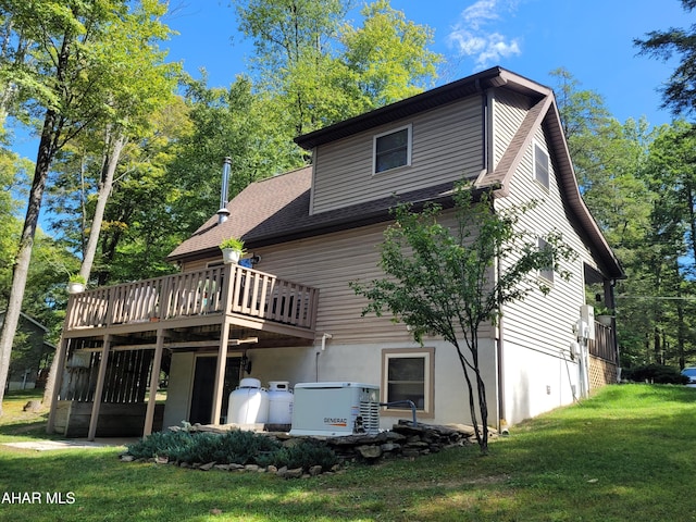 rear view of property featuring a deck, roof with shingles, and a lawn