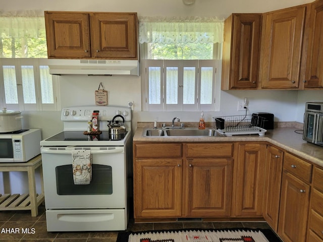 kitchen featuring dark tile patterned flooring, white appliances, and sink